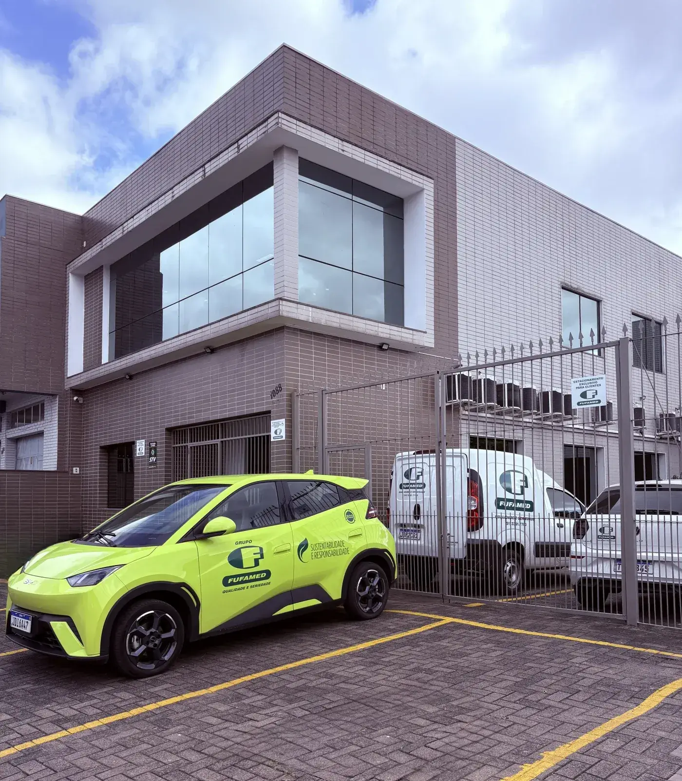 Sede da Fufamed em Porto Alegre, com o carro elétrico da empresa e a frota de entrega estacionados
